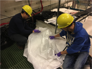 Jingbo and Marcus are cleaning a Hefty bag to use in the tank. 